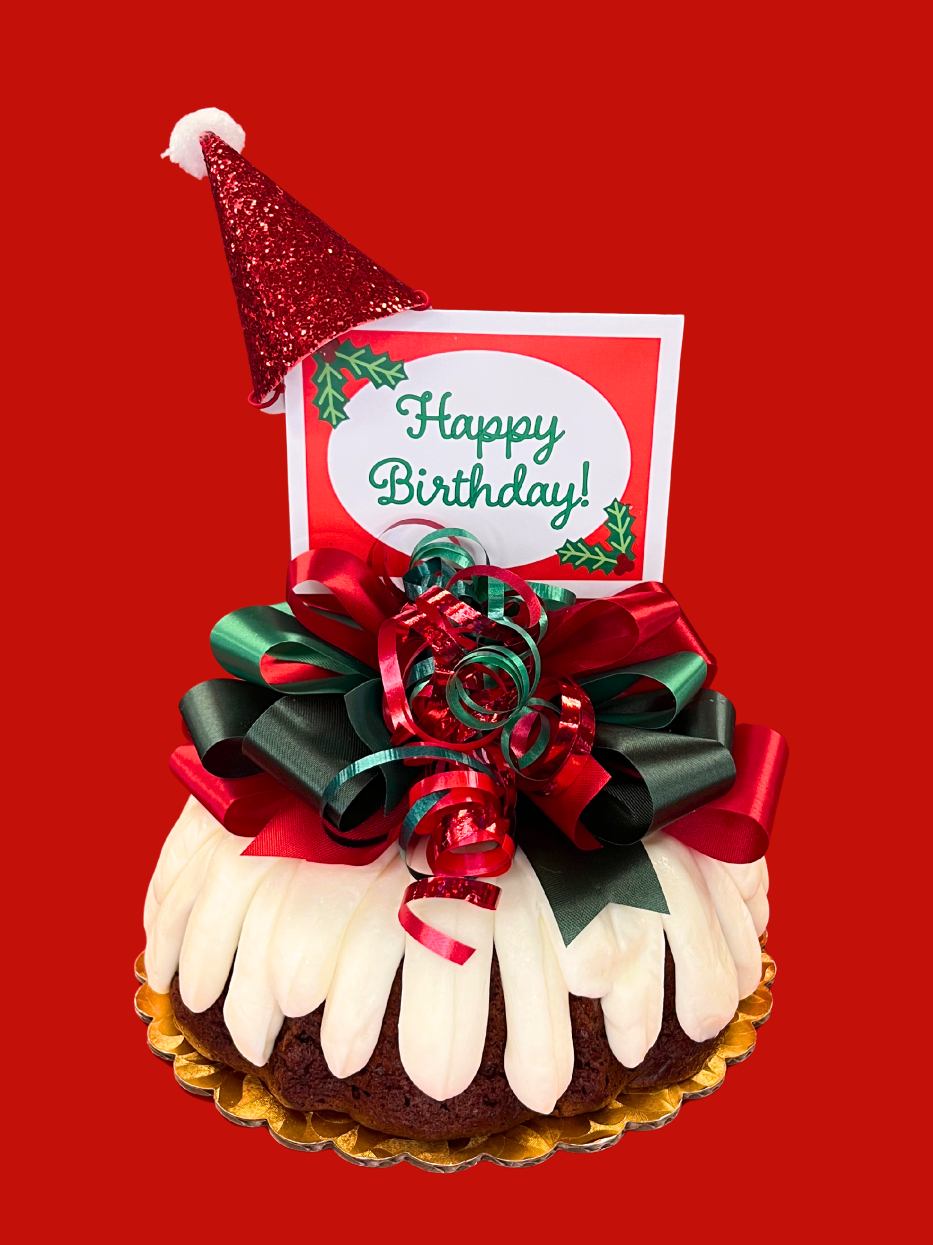 Decorative holiday birthday bundt cake with red and green ribbons and a 'Happy Birthday!' card on a red background