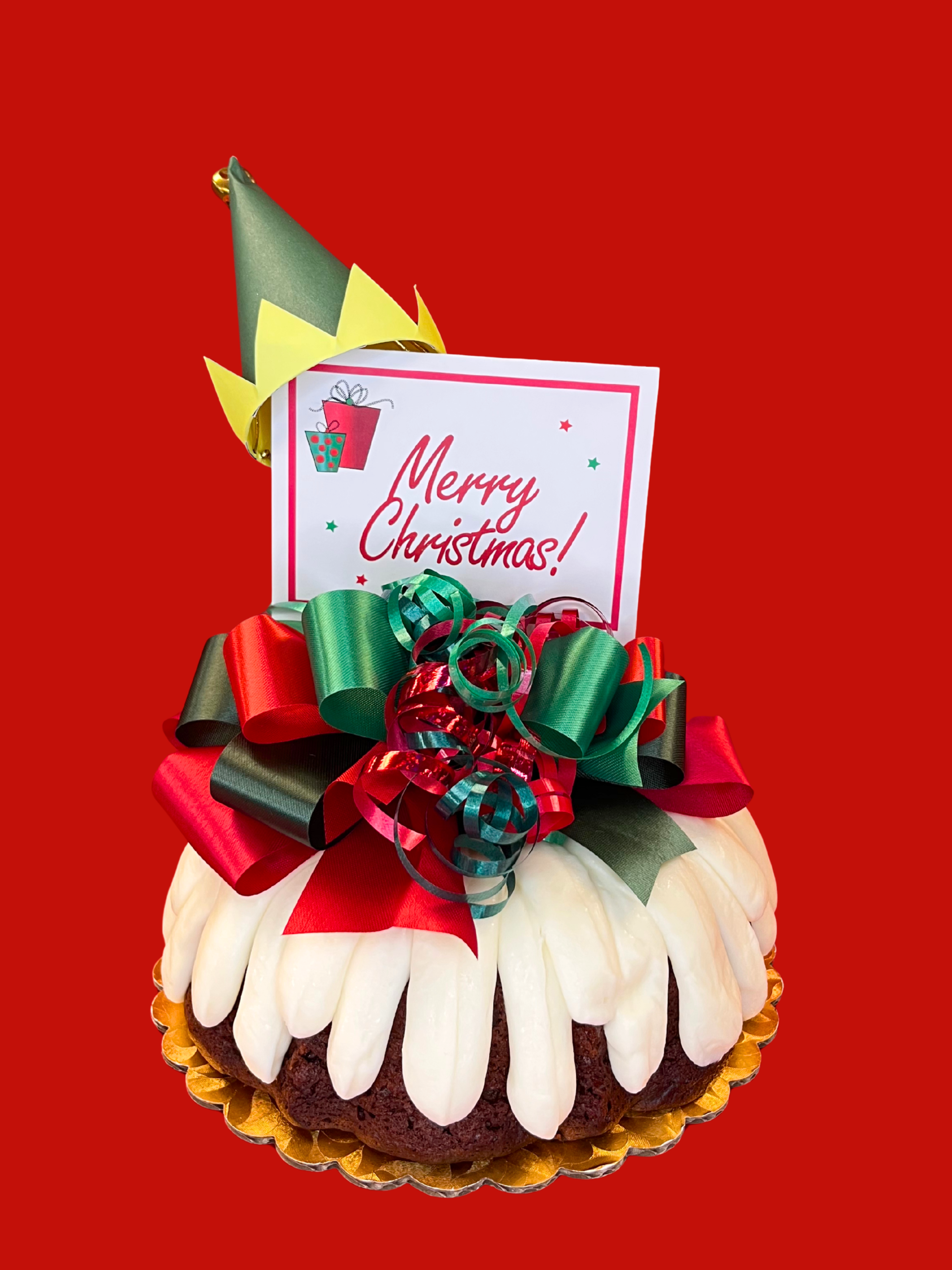 Elf Hat on a Bundt decoration on a bundt cake with white cream cheese frosting on a red background.