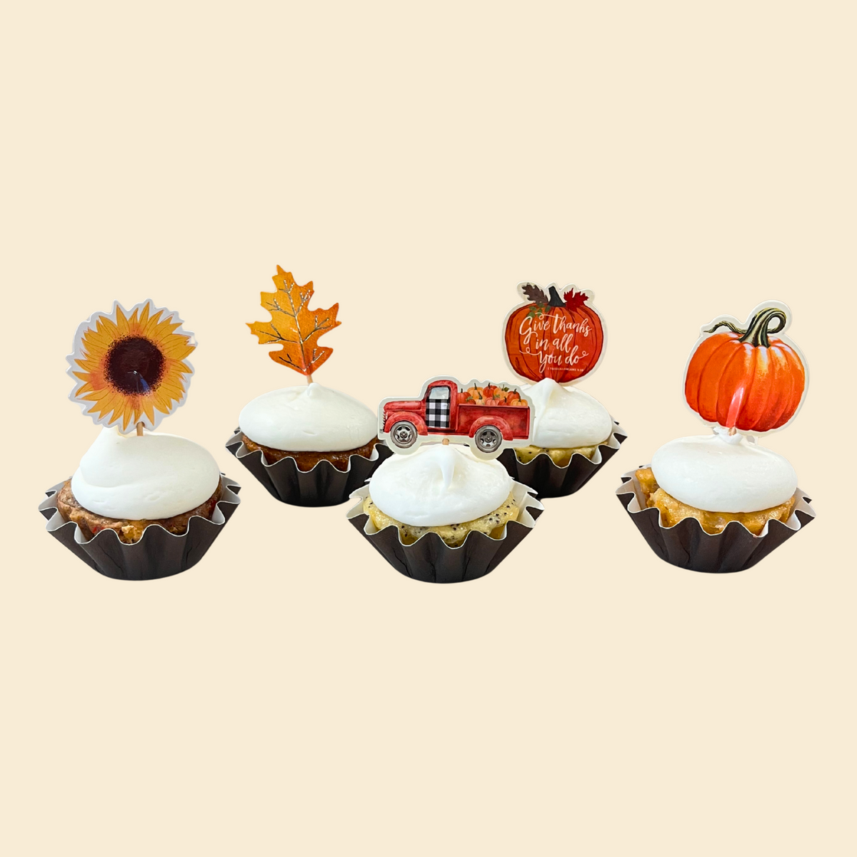 Set of five decorative cupcake toppers with autumn-themed designs on a beige background.